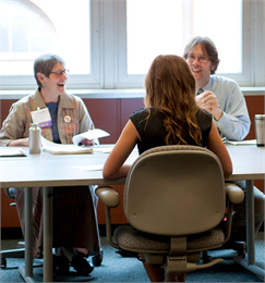 Two judges smile and laugh as they interview a National History Day student.