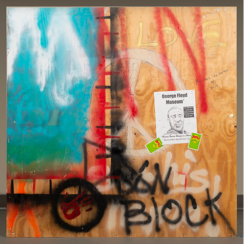 Graffiti'd wood panels from the Wisconsin Historical Museum, featuring colorful splashes and a printed poster of George Floyd Titled the George Floyd Museum, some hard to discern text. BLM in artful bubble letters and the phrase 'always lies'.